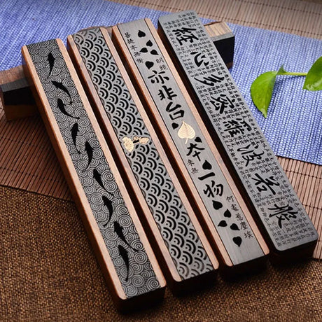 Wooden incense sticks with engraved designs on a textured surface