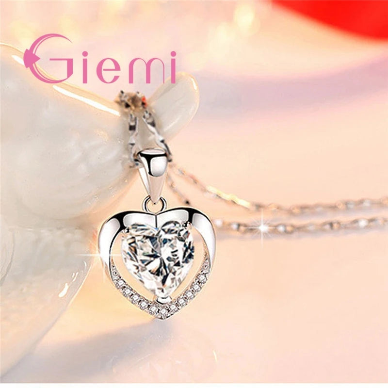 Heart-shaped silver pendant with clear gemstone on a soft background, featuring the brand 'Giemi'.