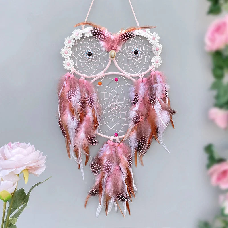 Decorative dreamcatcher with pink feathers and flowers on a light gray background