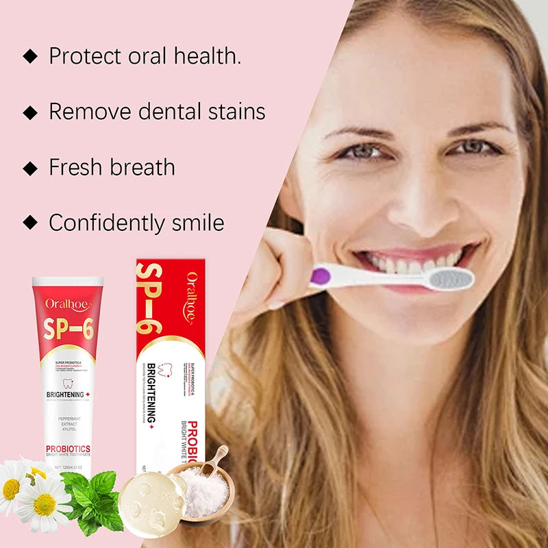 Woman holding a toothbrush with Oral-B toothpaste and toothbrush packaging on a pink background.