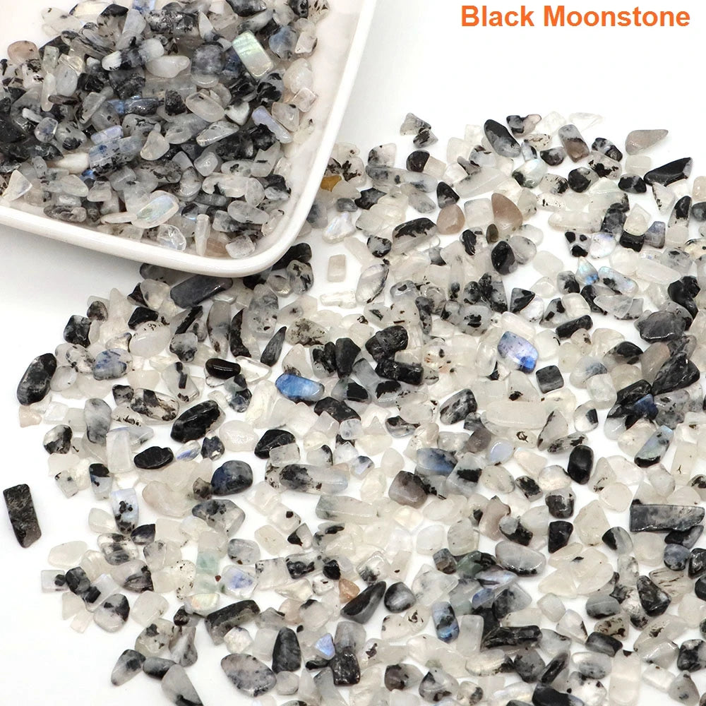 Black moonstone stones on a white surface with a small dish of stones.