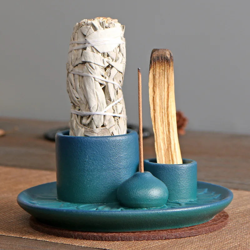 Teal ceramic holder with sage and incense sticks on a wooden surface