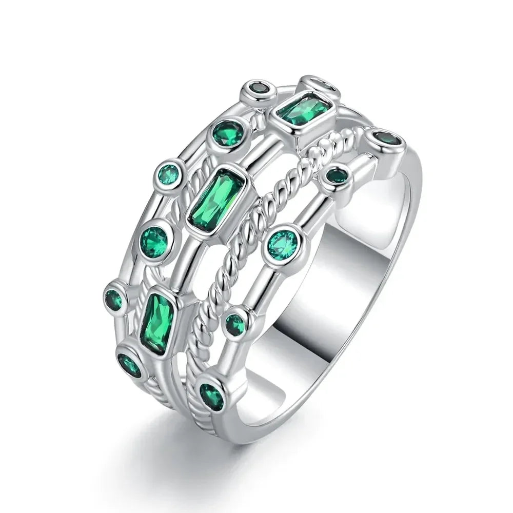 Silver ring with green gemstones on a white background