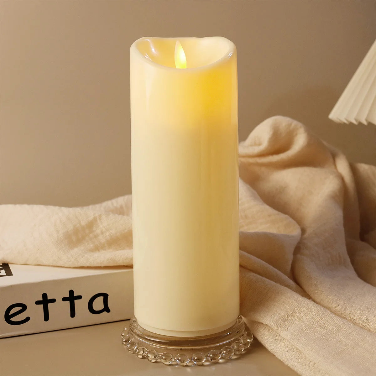 Lit candle in a decorative holder with soft fabric and a blurred 'etta' box in the background