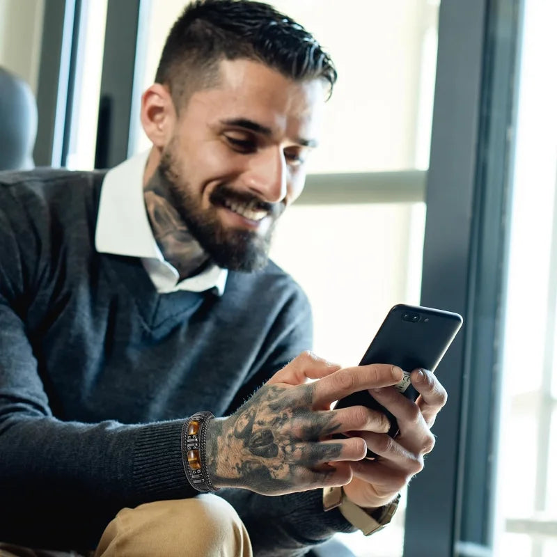 Man with tattoos using a smartphone indoors