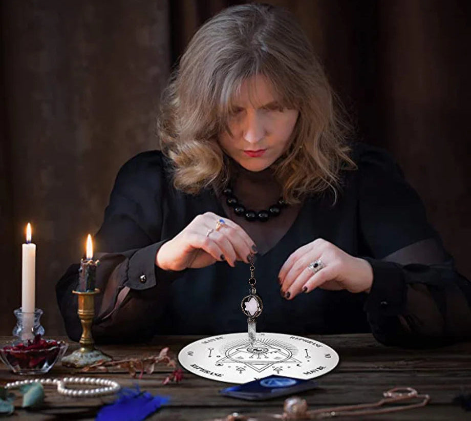 Woman in a dark outfit with candles and a tarot card on a table, possibly a fortune teller or psychic.