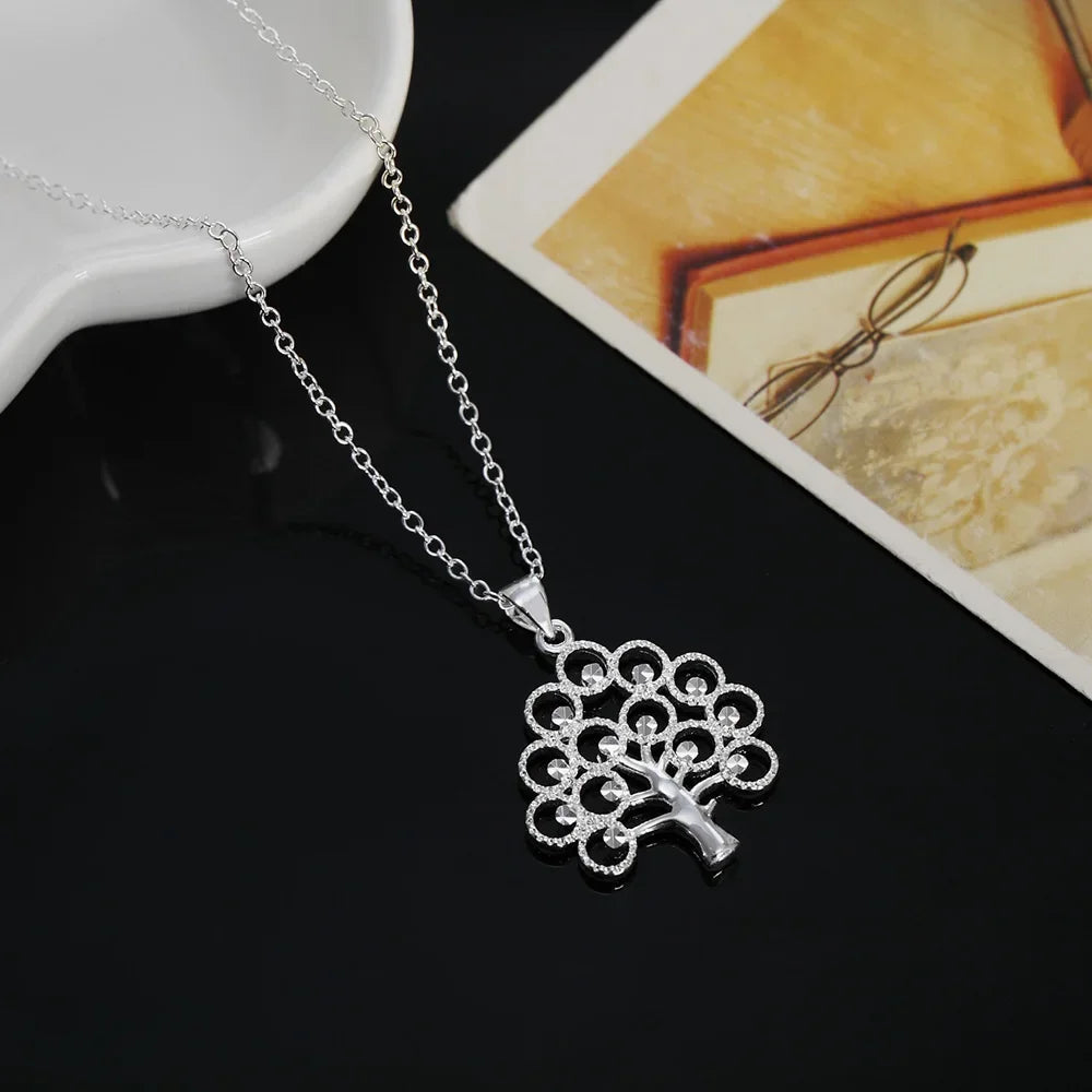Silver necklace with a tree-shaped pendant on a dark surface.