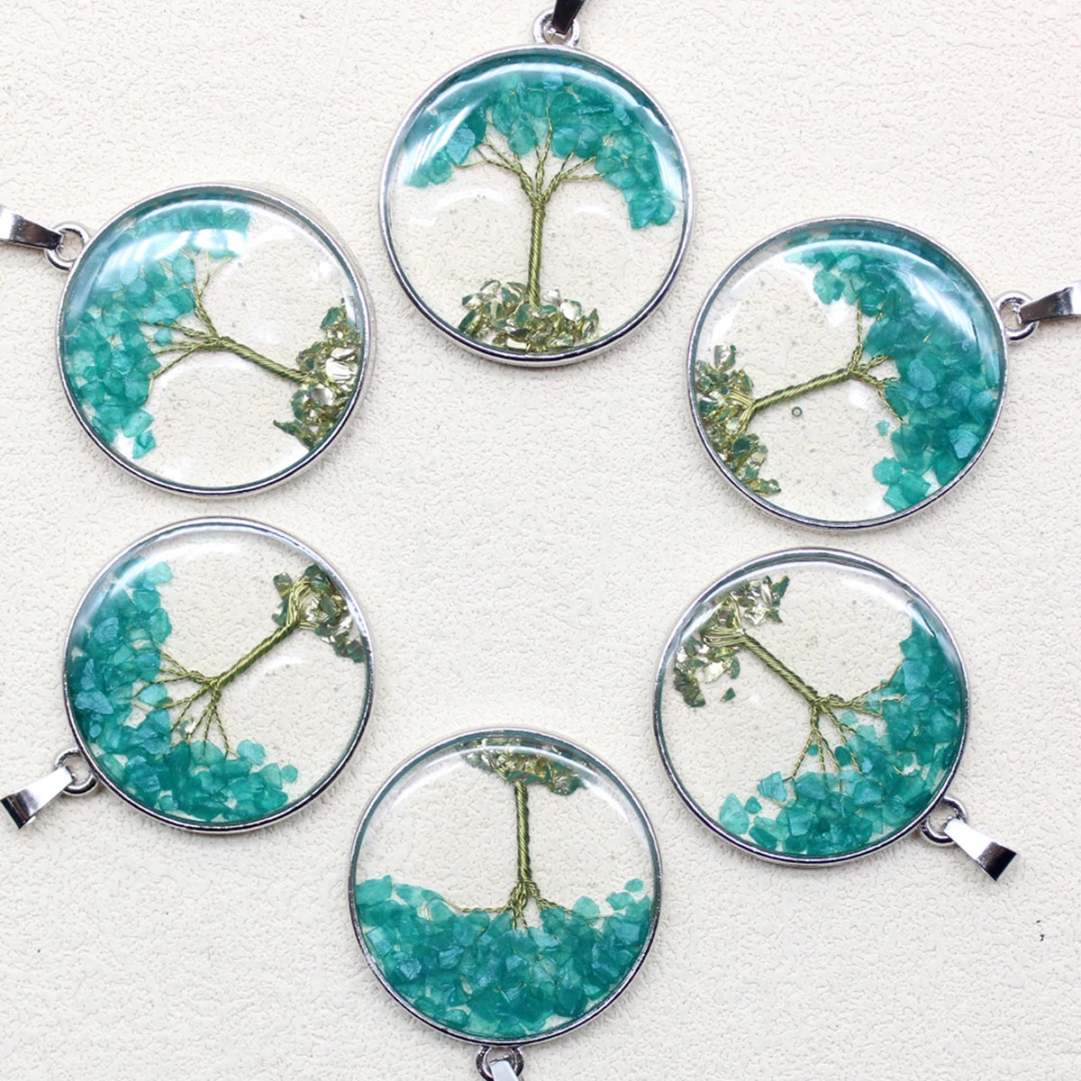 Set of six circular pendants with green tree designs on a white background
