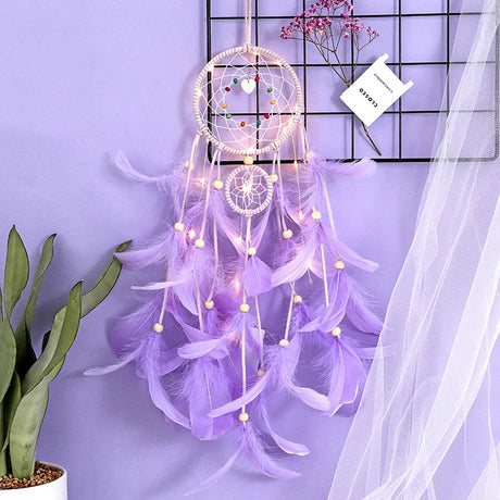Decorative dreamcatcher with feathers and lights on a purple background