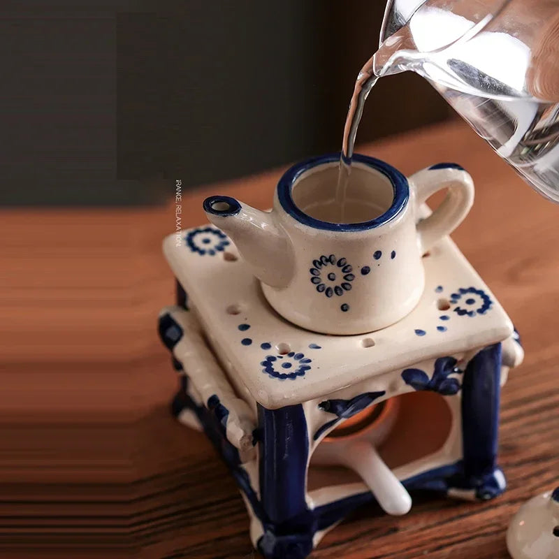 Ceramic teapot and cup set with blue floral patterns on a wooden surface, being filled with hot liquid.