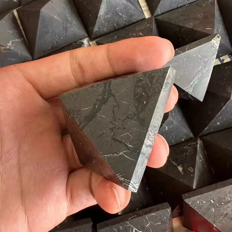 Hand holding a triangular marble tile with more tiles in the background
