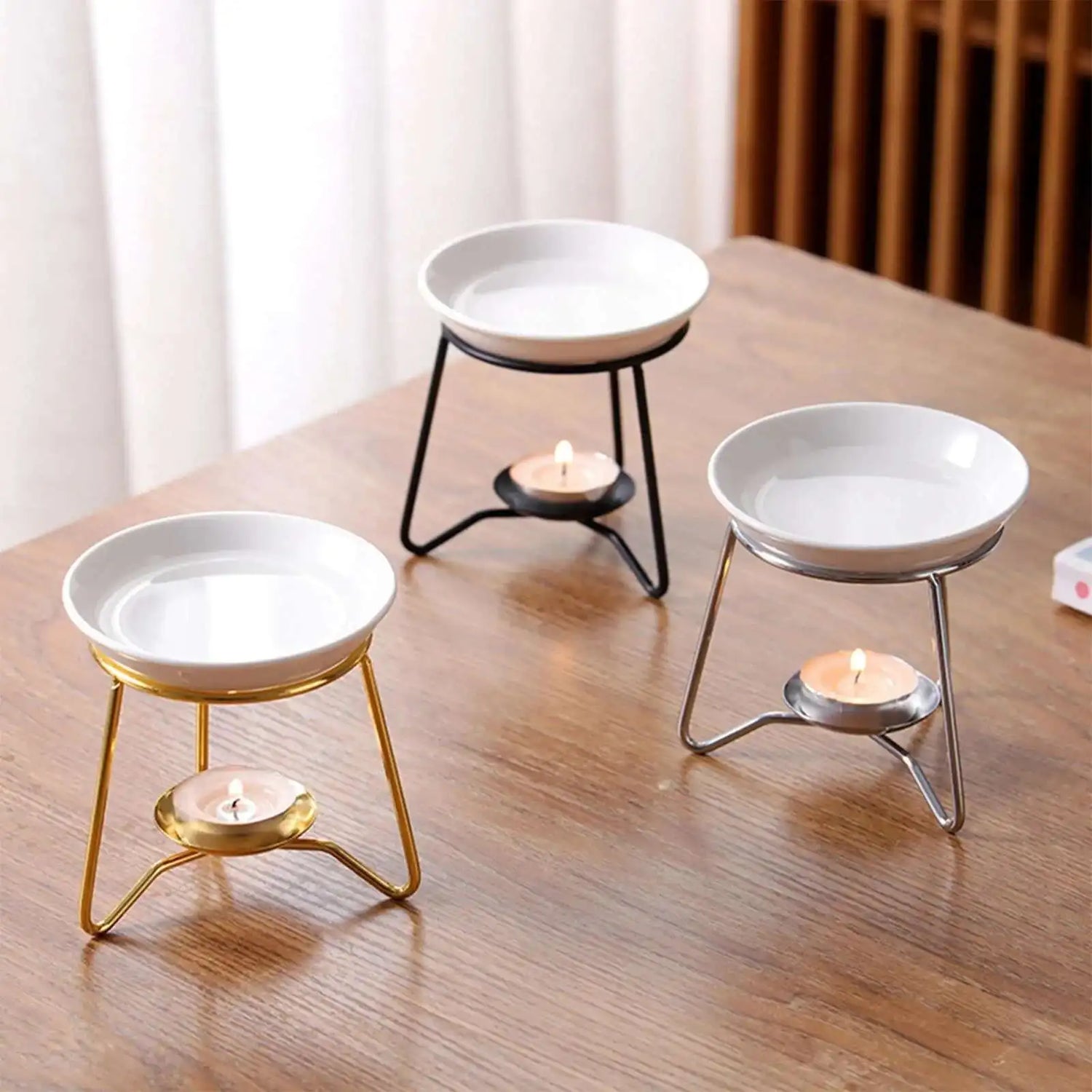 Three white candle holders with different base colors on a wooden surface.