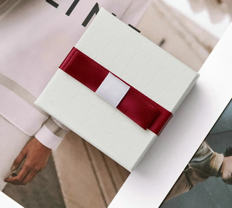 White gift box with a red ribbon on a blurred background