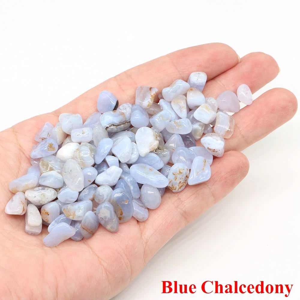 Hand holding a small pile of blue chalcedony stones on a white background