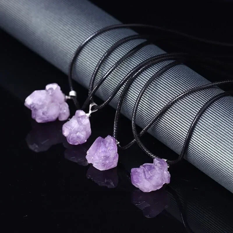 Purple crystal pendants on black strings against a dark background