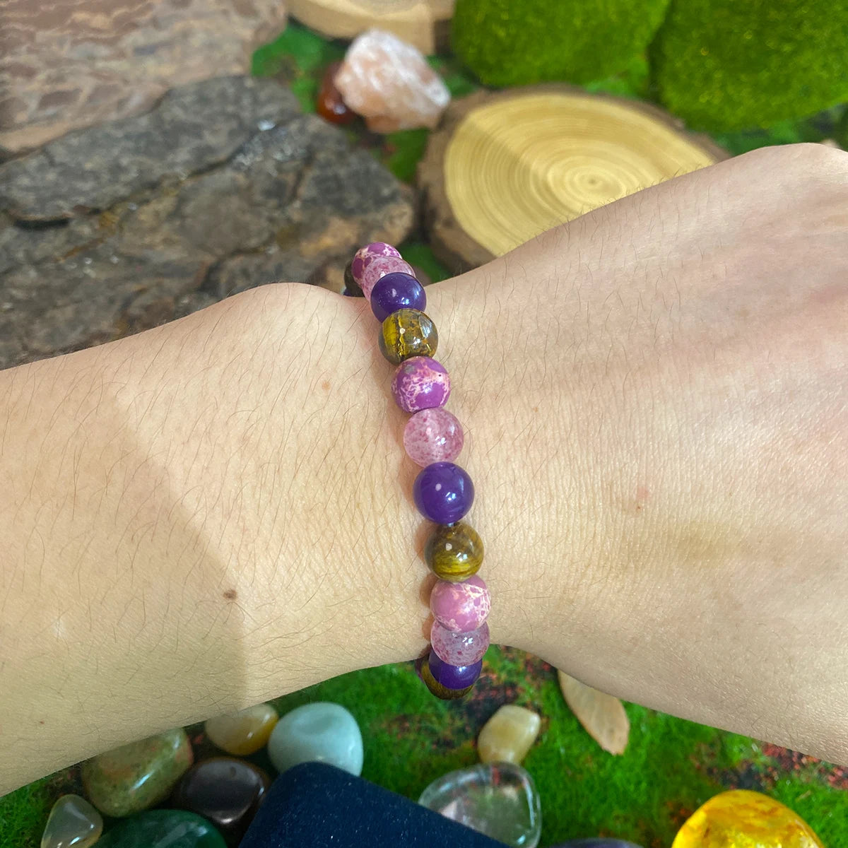 Multicolored beaded bracelet on a wrist with a natural stone background