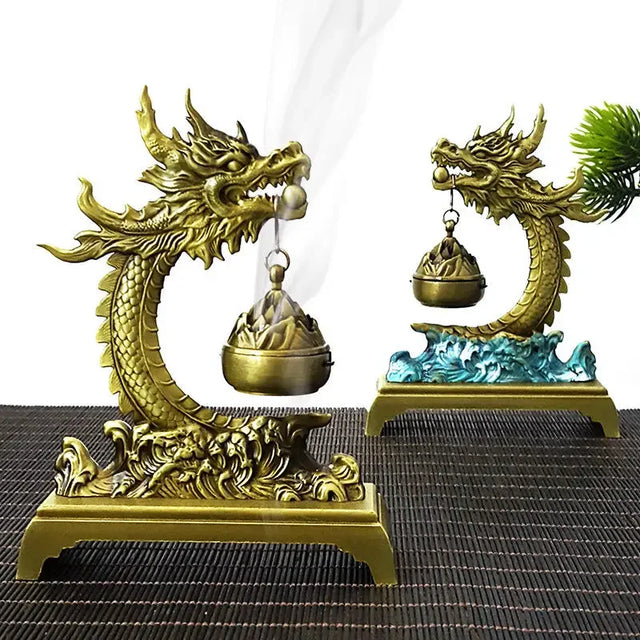 Two gold dragon-shaped incense burners on a textured surface.