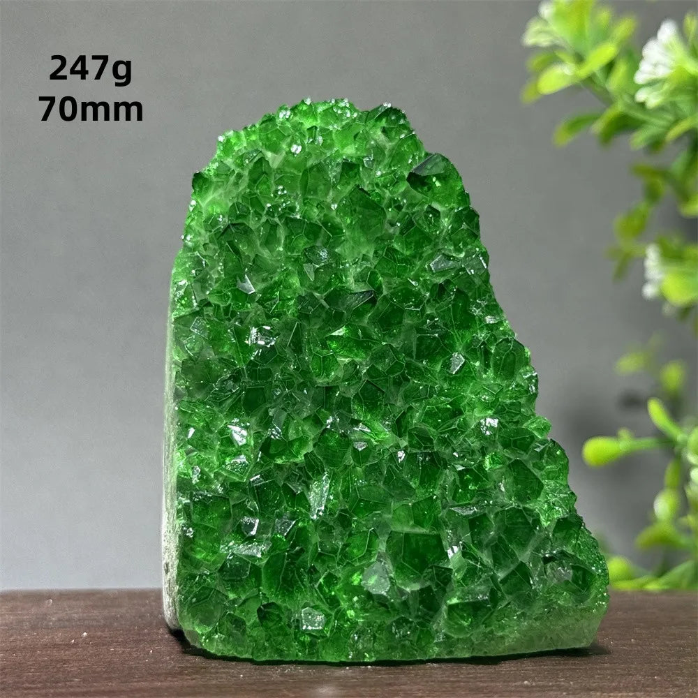 Green crystal rock on a wooden surface with a plant in the background