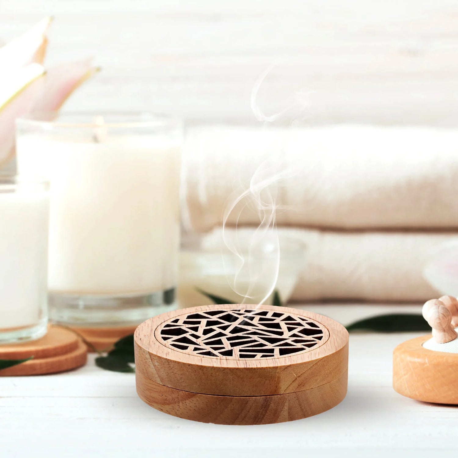 Wooden incense burner with smoke emitting, surrounded by candles and a blurred background