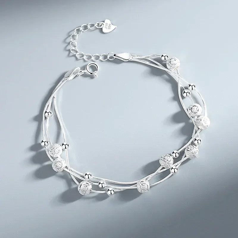 Silver bracelet with floral and bead design on a light gray background