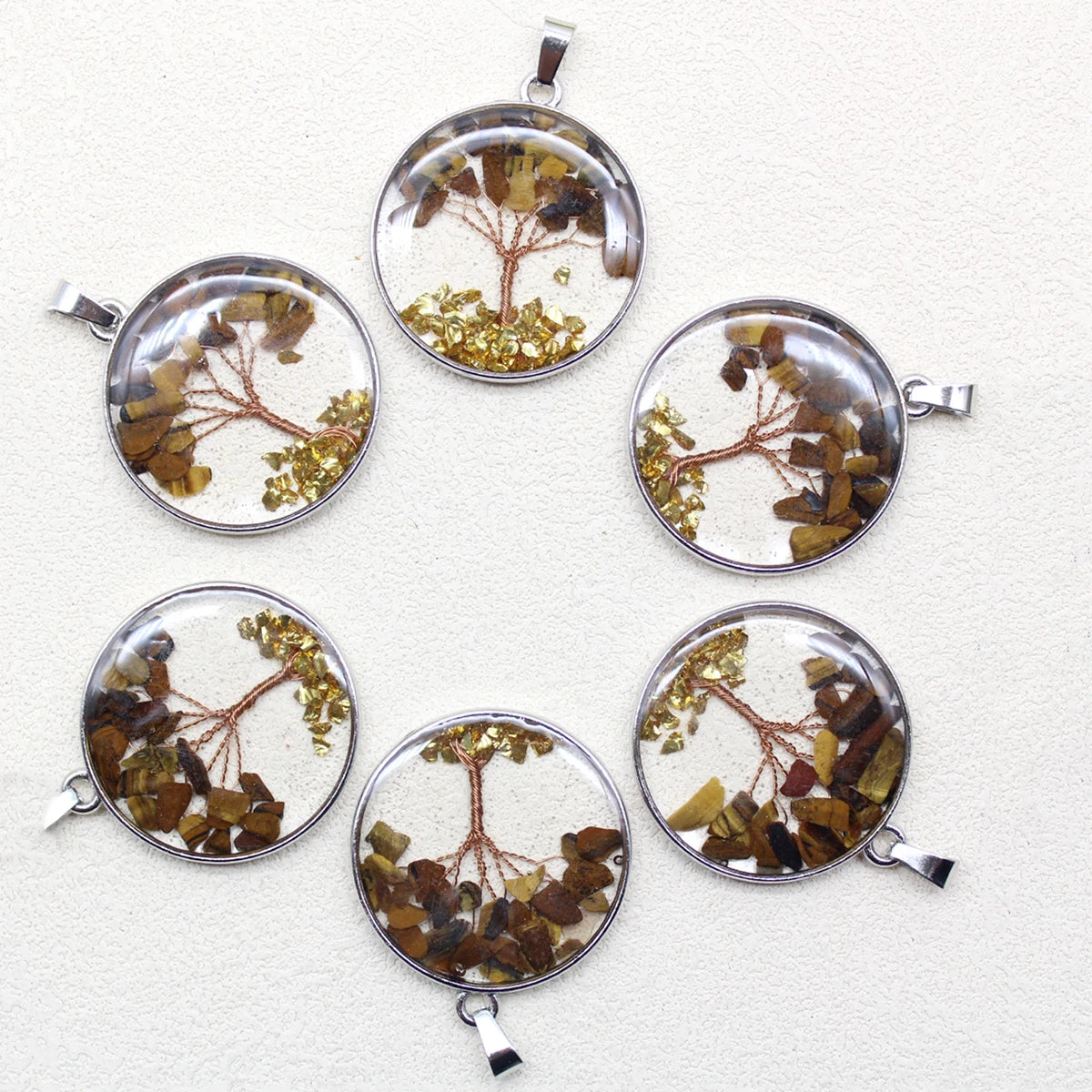 Six round pendants with embedded tree branches and leaves on a white background