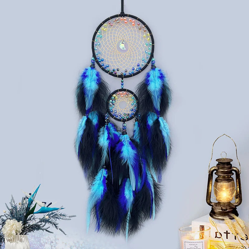 Blue and black dreamcatcher with feathers against a light gray background