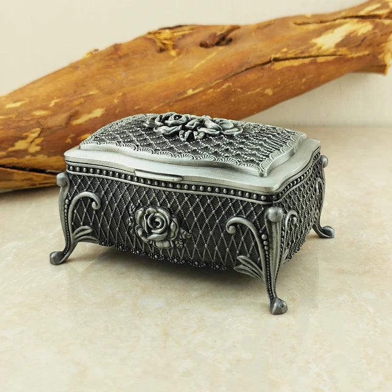 Decorative silver jewelry box with floral designs on a beige surface