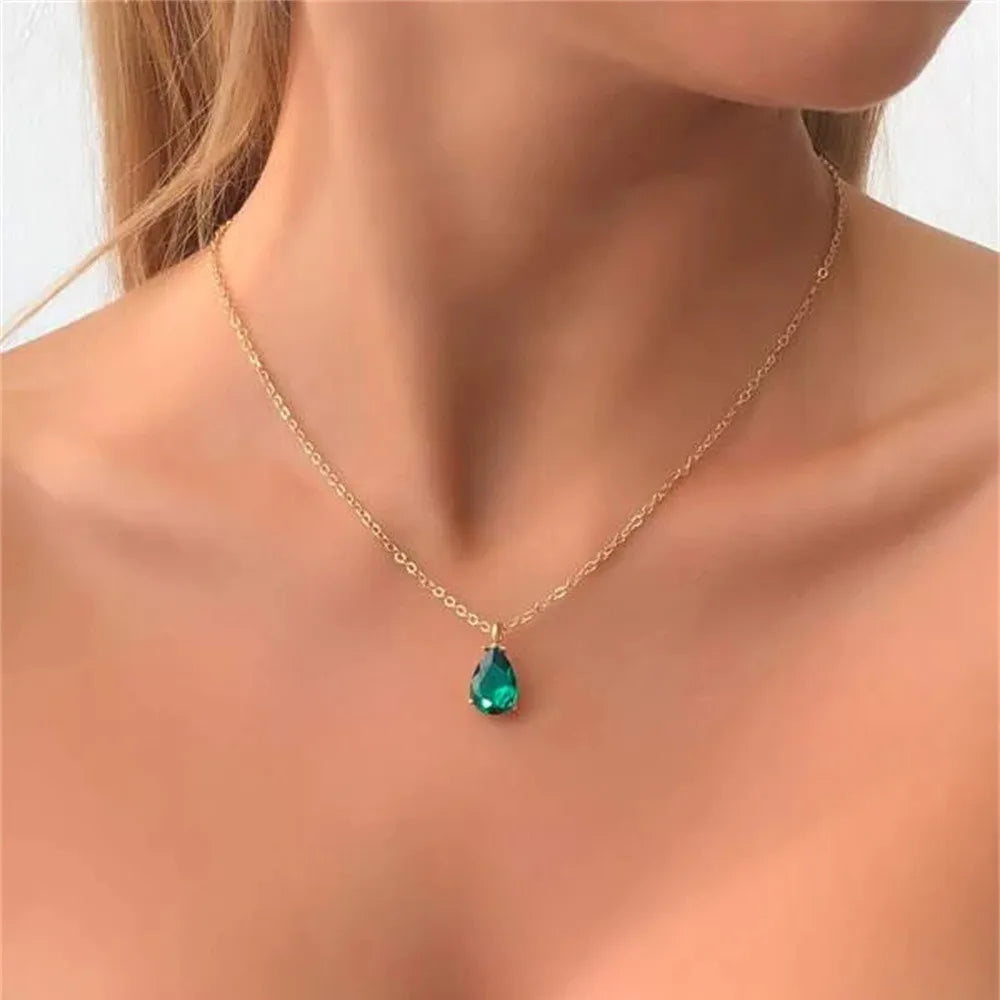Gold necklace with a green teardrop pendant on a model