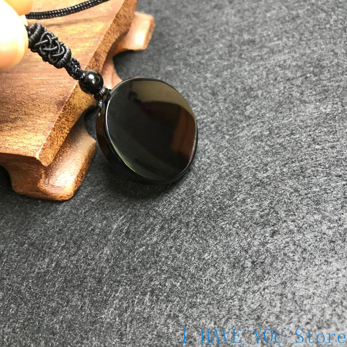 Black stone pendant on a wooden stand with a gray background