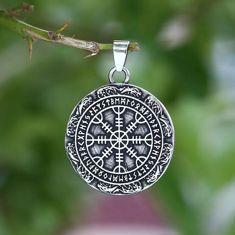 Silver Vegvisir pendant on a branch with a blurred green background