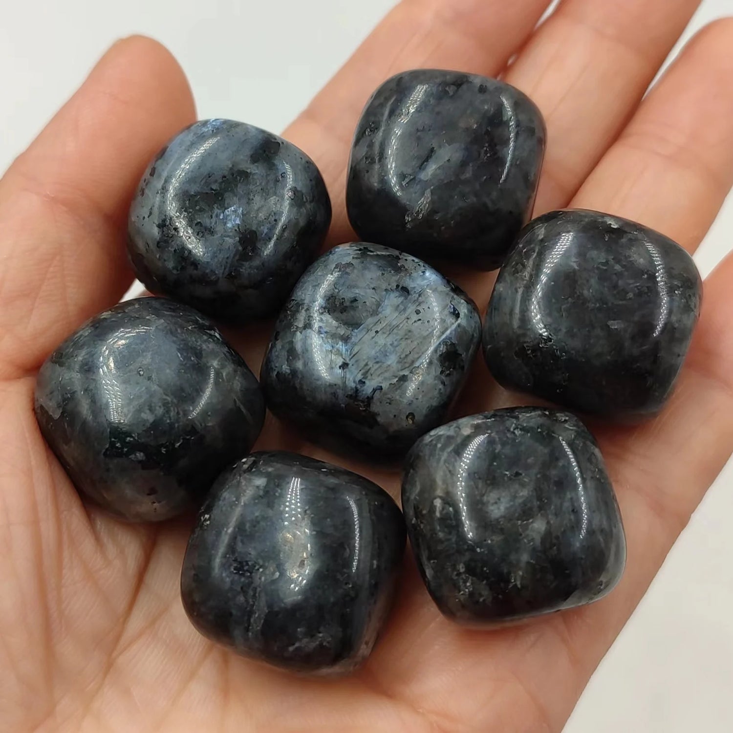 Hand holding seven dark gray stones against a white background