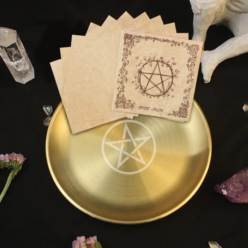 Gold bowl with pentagram design, cards with pentacle symbol, and crystals on a dark surface