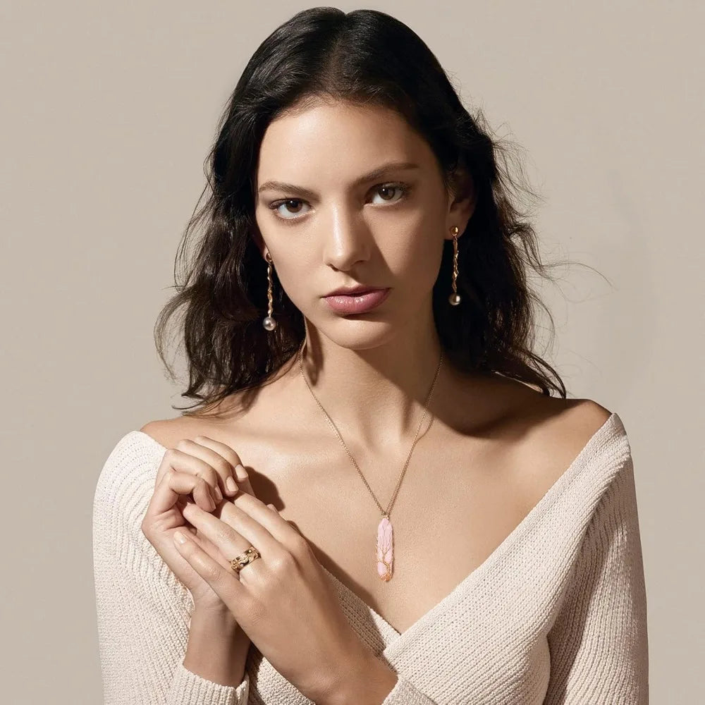 Woman wearing jewelry including a necklace, earrings, and ring against a neutral background