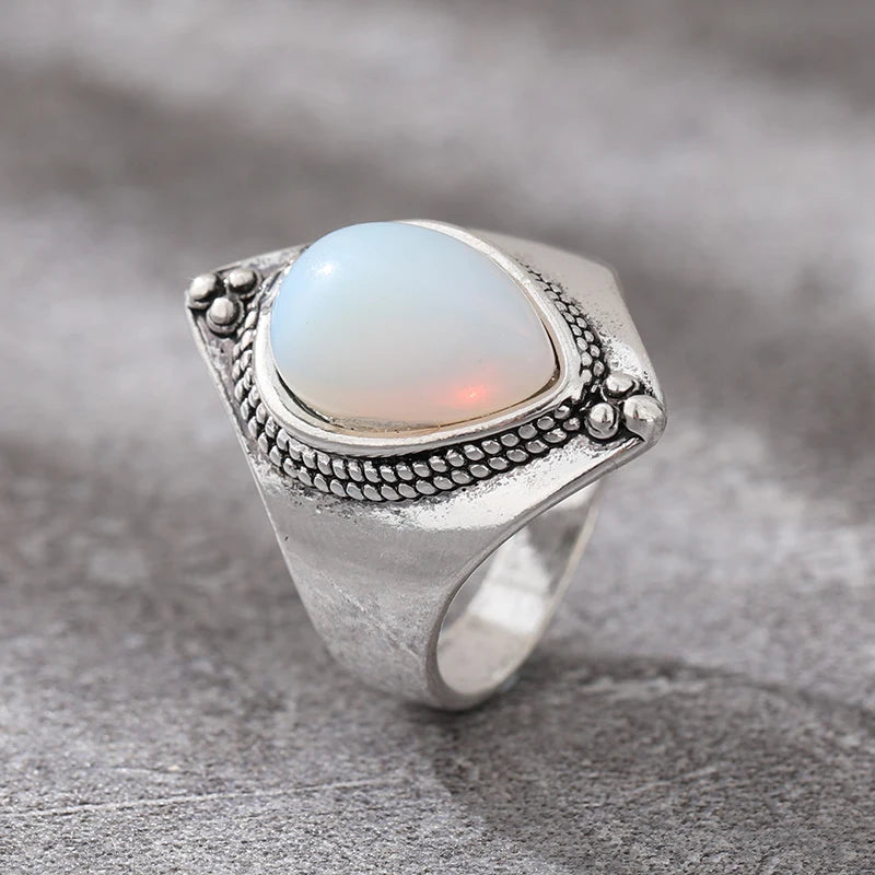 Silver ring with an opal stone on a gray surface