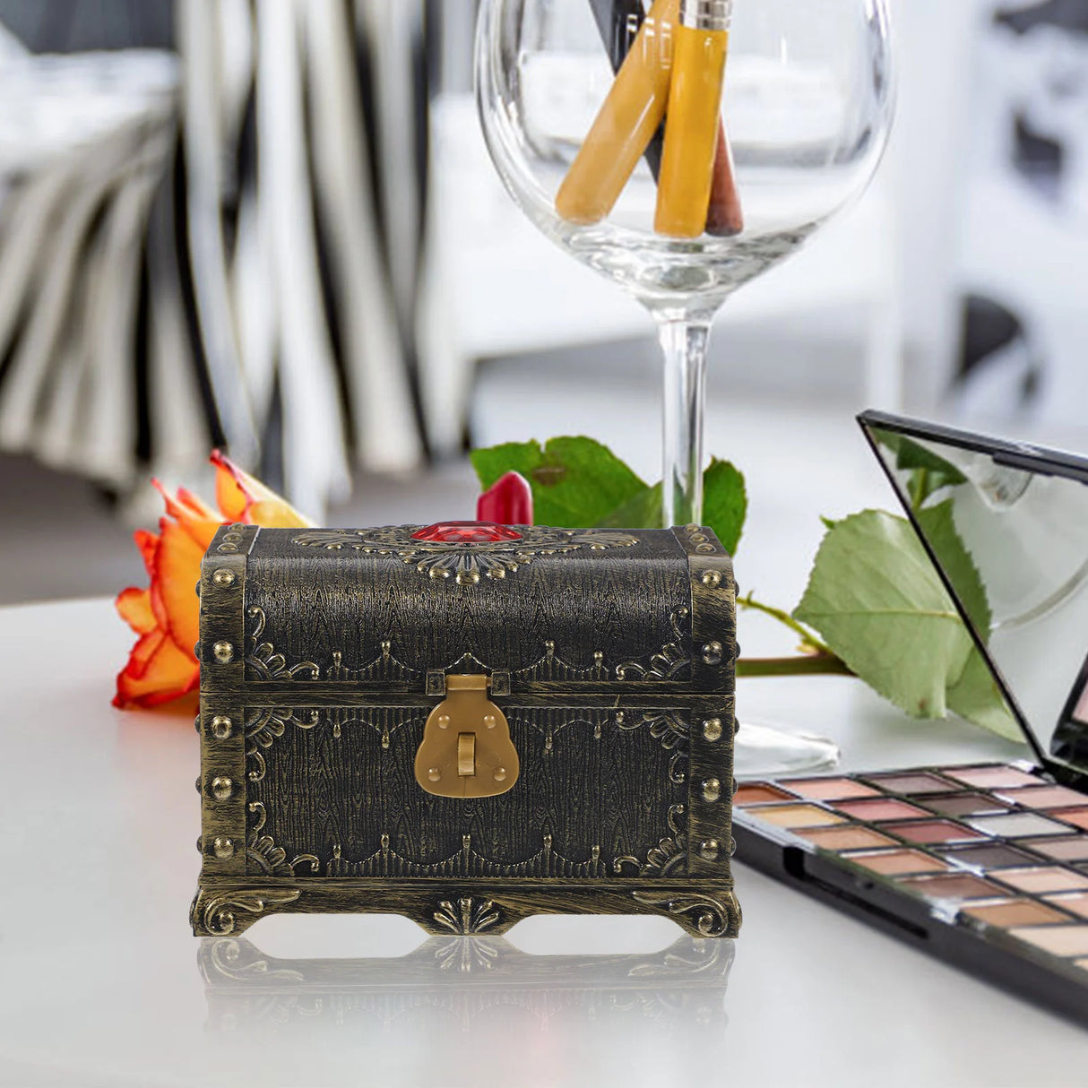 Decorative chest on a table with makeup palette and wine glass in the background