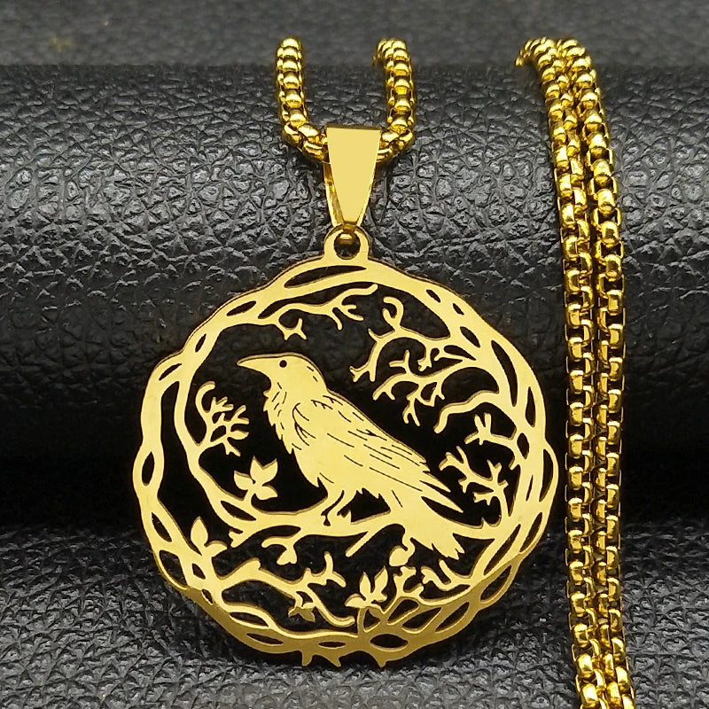 Gold bird pendant with chain on a black textured surface