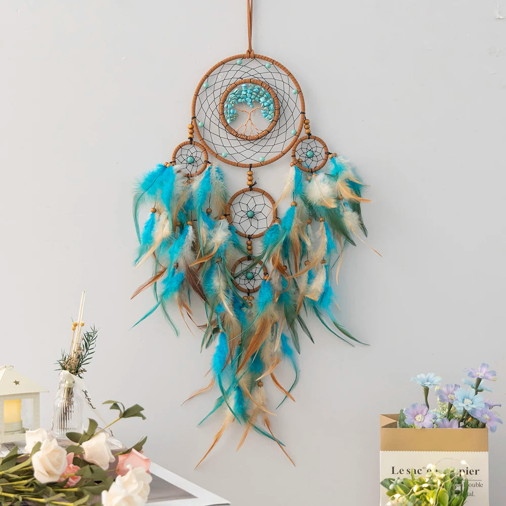 Decorative dreamcatcher with feathers on a light gray wall.