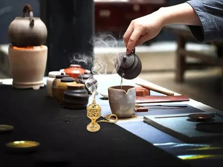 Person pouring tea from a teapot into a cup on a tea table with various tea-making items.