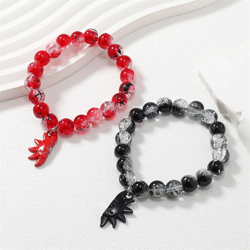 Two beaded bracelets, one red and one black with clear beads, on a white surface.