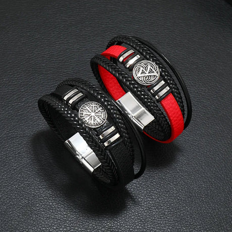 Two black leather bracelets with red accents and silver metal clasp on a dark textured surface