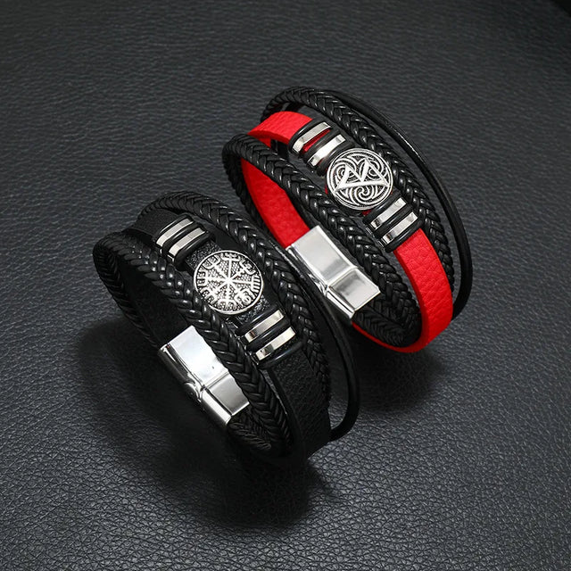 Two black leather bracelets with red accents and silver metal clasp on a dark textured surface