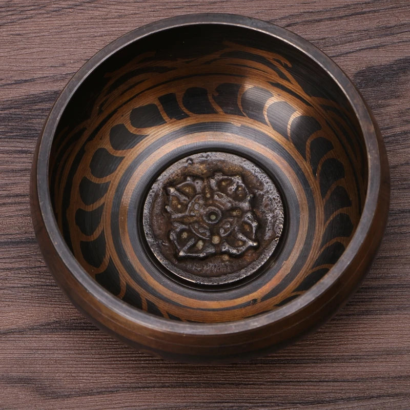 Decorative bronze bowl with intricate patterns on a wooden surface
