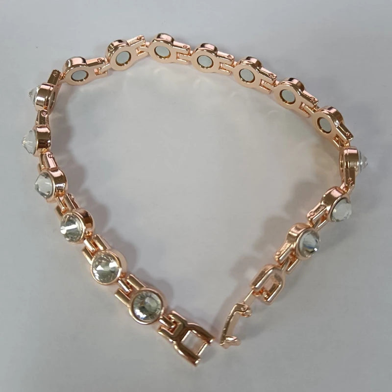 Rose gold bracelet with clear gemstones on a light gray background