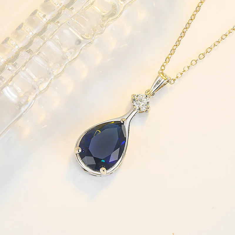 Gold necklace with a blue teardrop pendant on a light background