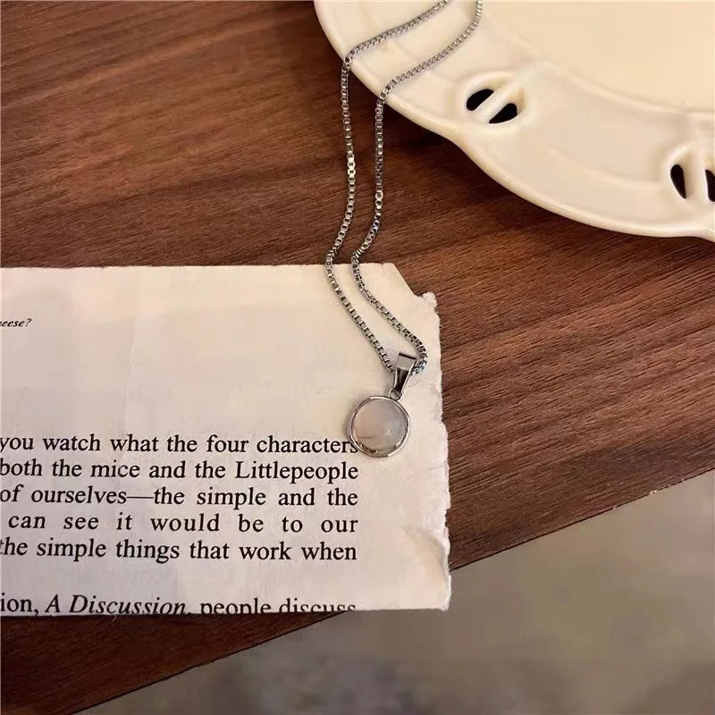 Necklace with a pendant on a piece of paper and wooden surface