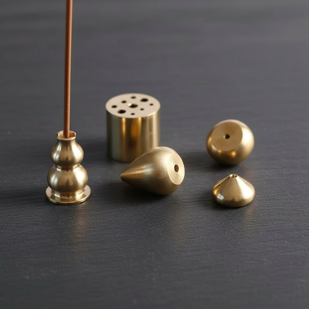 Set of gold-colored metal incense holders on a white background