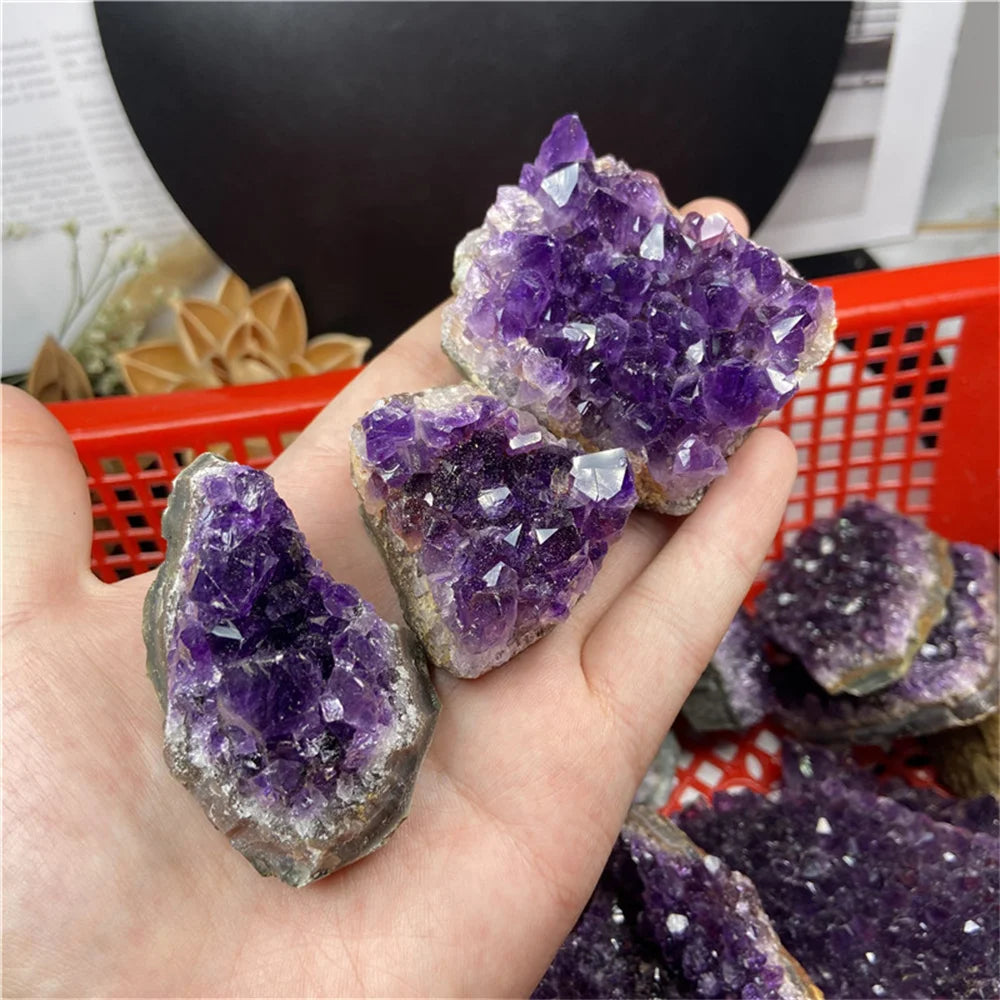 Hand holding a purple crystal formation with a blurred indoor background