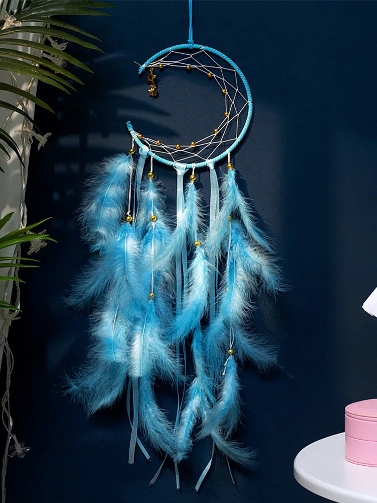 Blue dreamcatcher with feathers against a dark blue wall