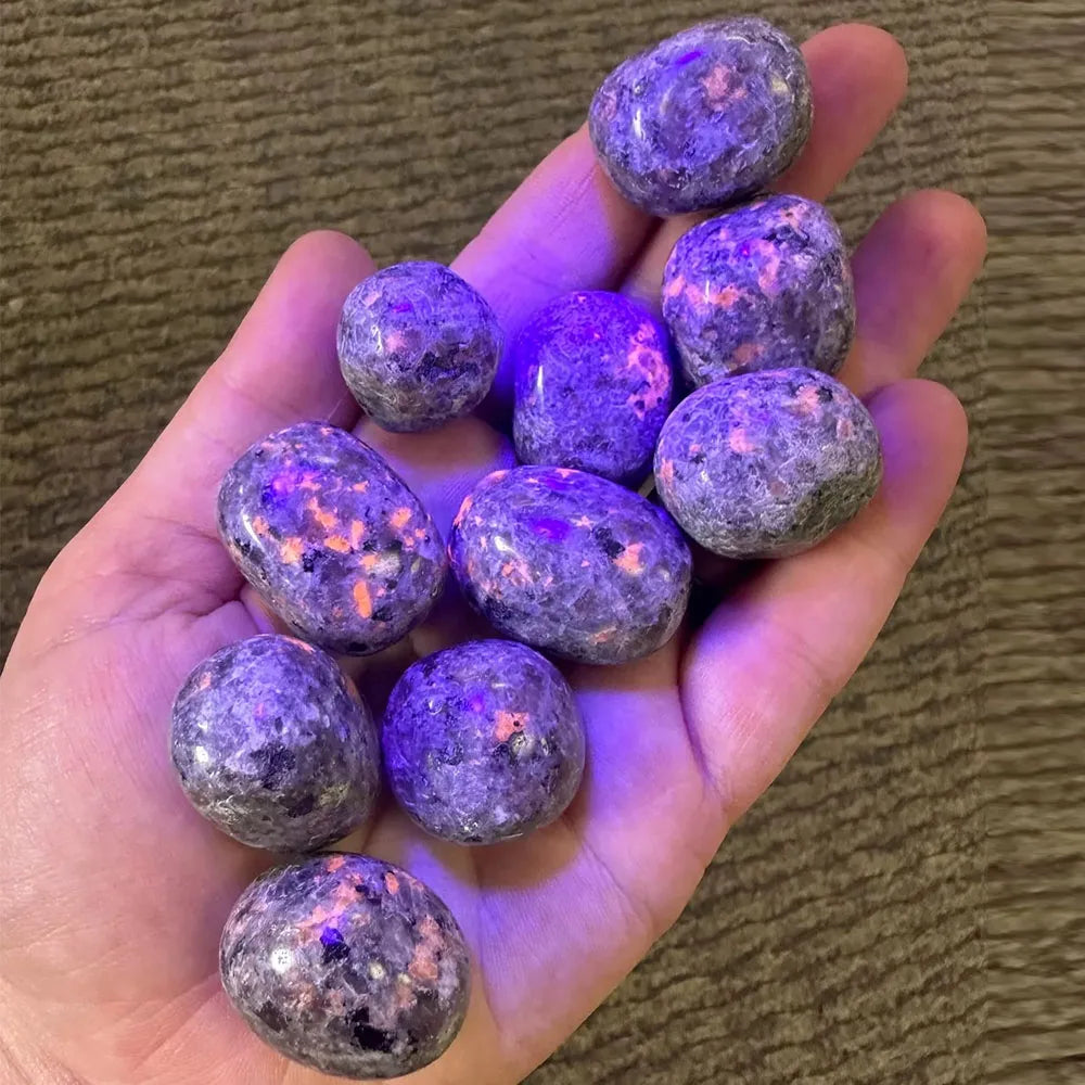 Hand holding purple and gray marbled stones against a brown background