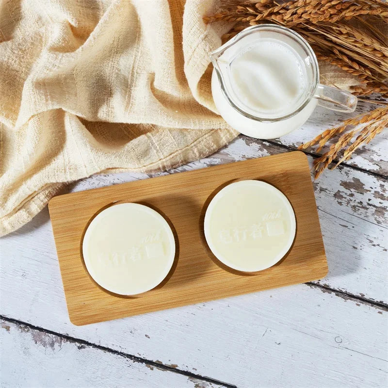 Two round white items on a wooden board with a glass container of liquid on a rustic wooden surface.